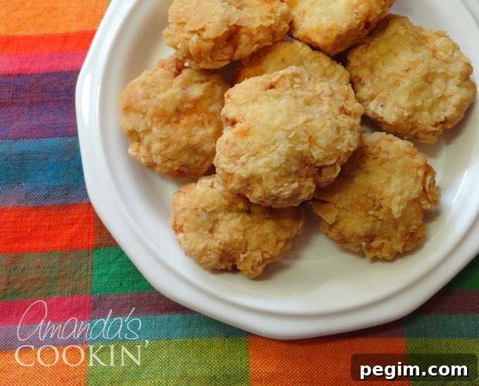 Crispy Homemade Chicken Nuggets Recipe 2 A close up overhead photo of homemade chicken nuggets on a white plate.