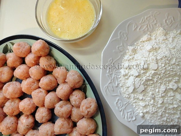 homemade-chicken-nuggets-step-8 A photo of a plate of raw chicken balls, a bowl of whisked eggs and a plate of flour and salt.