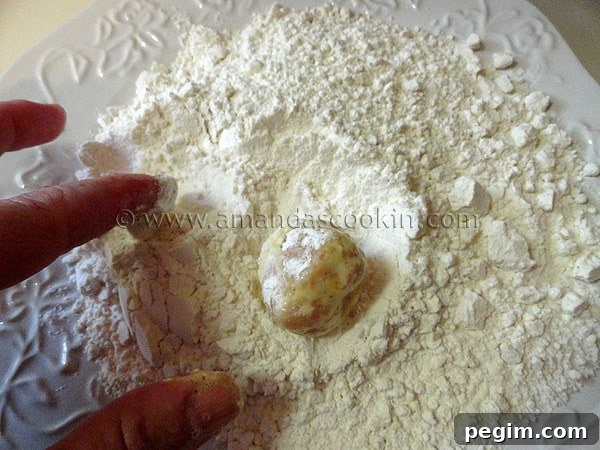 homemade-chicken-nuggets-step-11 A photo of the chicken ball being rolled in the flour mixture again after being coated in egg.