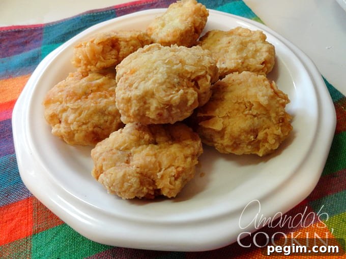 Crispy Homemade Chicken Nuggets Recipe 3 A close up overhead photo of homemade chicken nuggets on a white plate.