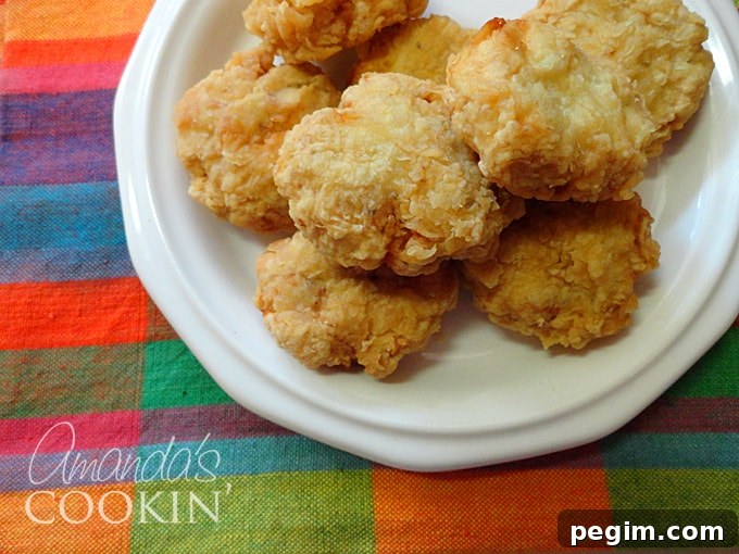 Crispy Homemade Chicken Nuggets Recipe 5 A close up overhead photo of homemade chicken nuggets on a white plate.