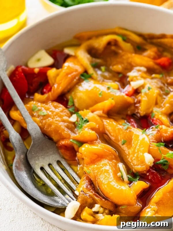 Classic Italian Pickled Peppers Recipe 11 Roasted peppers in a bowl with utensils inside.