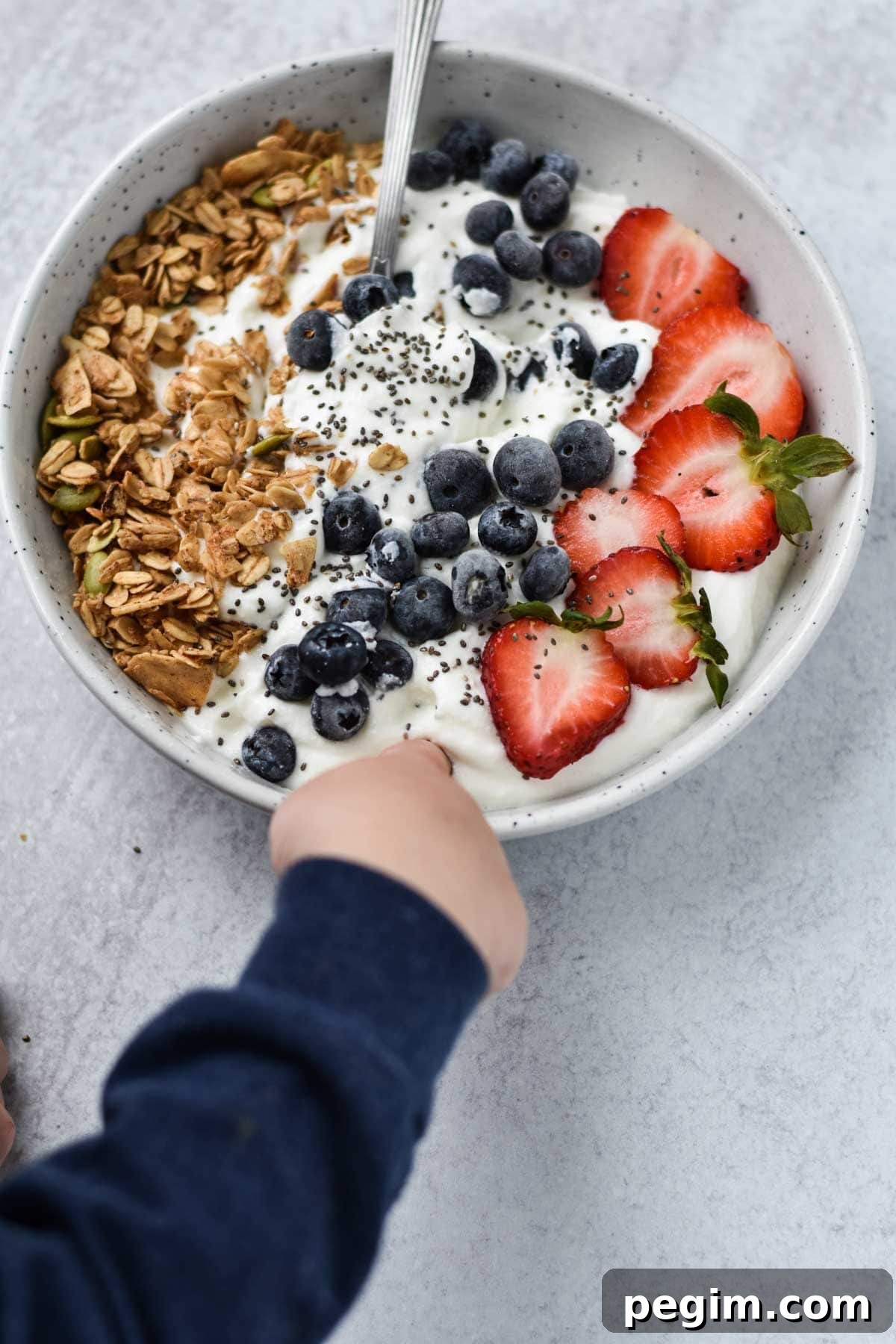 Cottage Cheese with Fruit: Tasty Breakfast and Snack Ideas 12 A child's hand poking their finger into a bowl of cottage cheese with fruit.