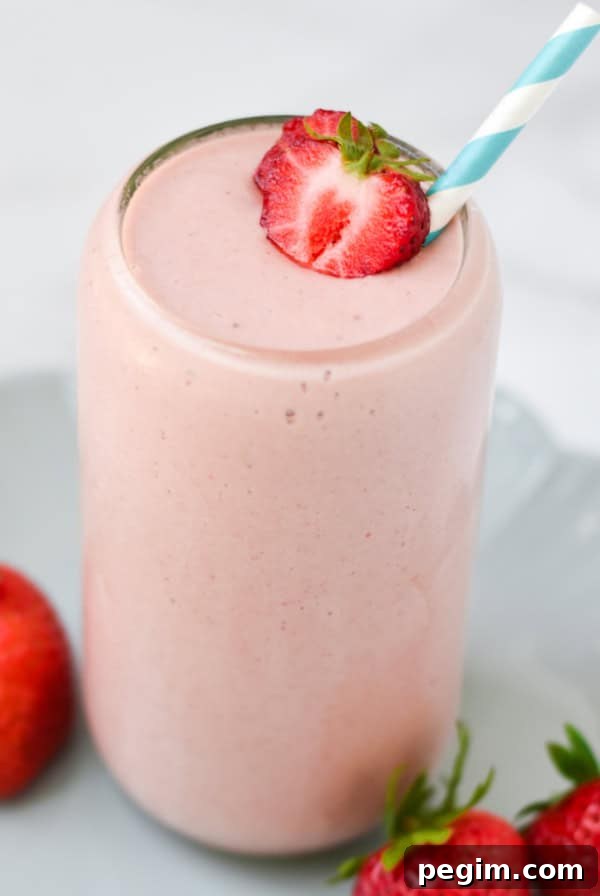 Cottage Cheese with Fruit: Tasty Breakfast and Snack Ideas 16 A strawberry cottage cheese smoothie with a blue straw on a plate.