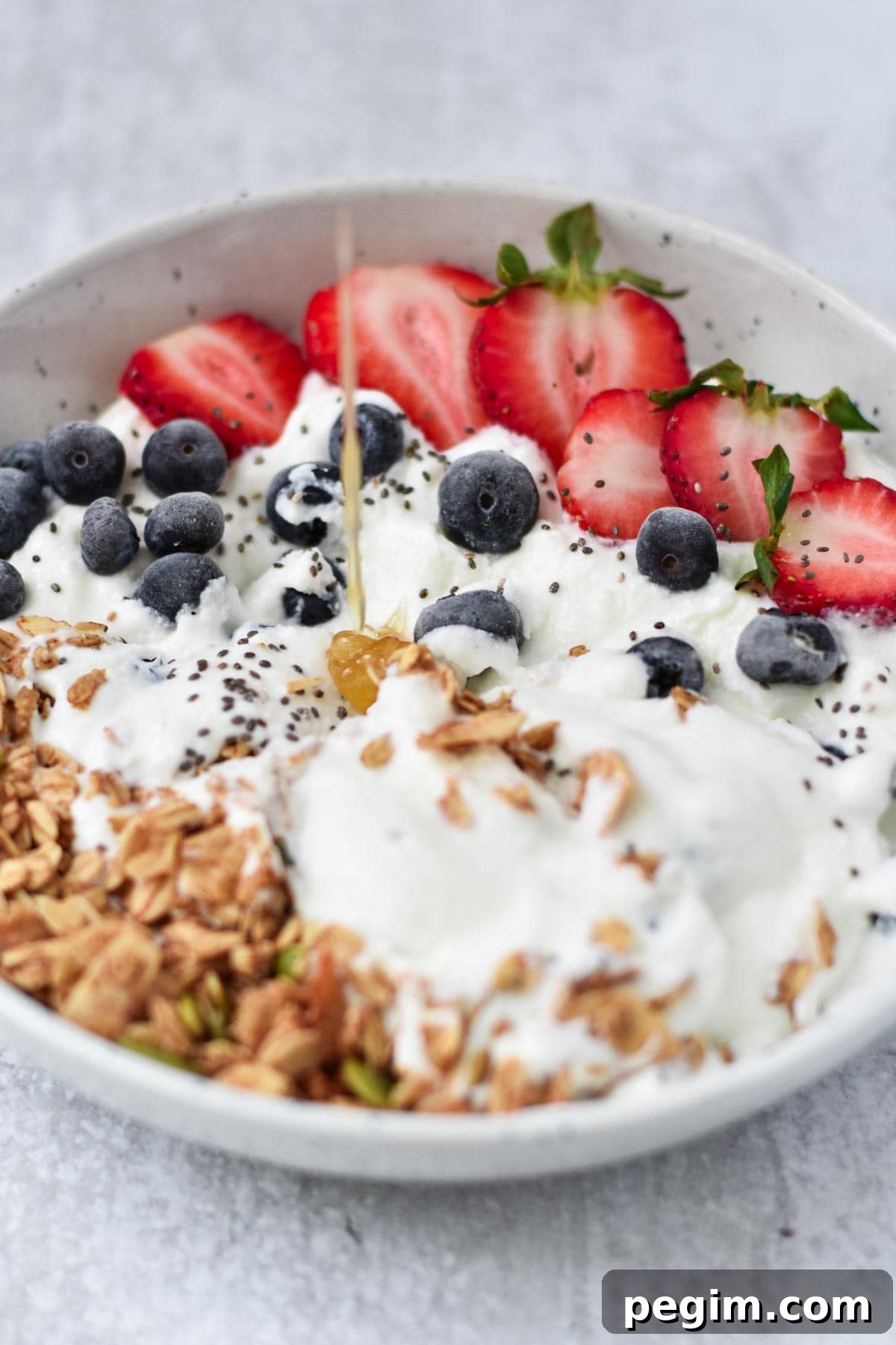 Cottage Cheese with Fruit: Tasty Breakfast and Snack Ideas 8 Honey poured onto a bowl of cottage cheese and berries.