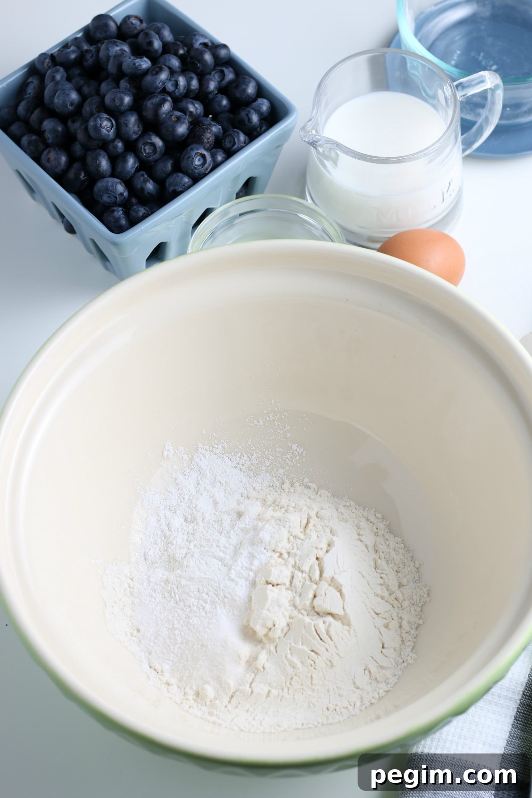 Fluffy Homemade Blueberry Pancakes 4 white glass bowl filled with dry ingredients for blueberry pancakes.