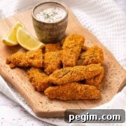 Keto air fryer fish sticks with a lemon wedge and tartar sauce.