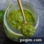 jar of pesto sauce with spoonful balancing on top