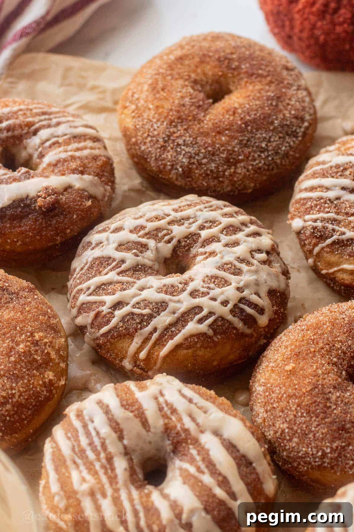 Homemade Apple Cinnamon Donuts with Spiced Glaze 2 Baked glazed apple cider donuts on parchment paper.