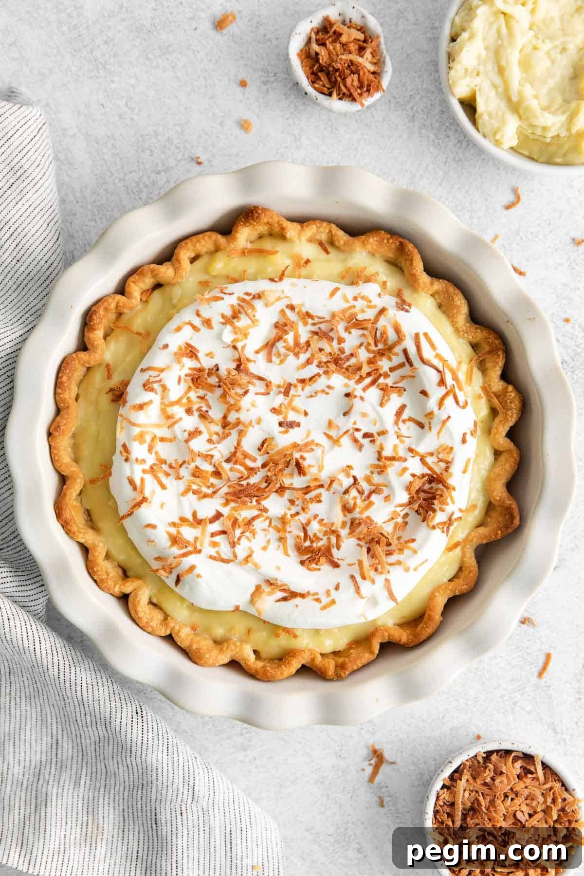 Vegan Coconut Cream Pie Recipe 2 Dairy-free coconut cream pie surrounded by coconut shreds and cream in a bowl