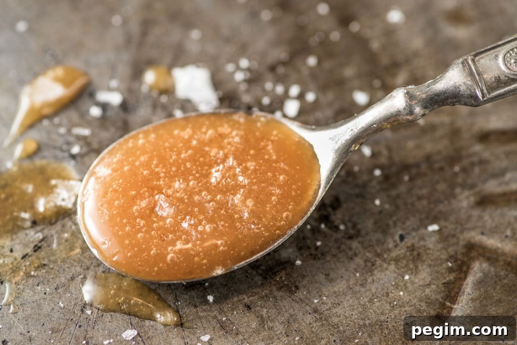 A spoonful of amber colored caramel sprinkled with coarse salt on a rustic pie tin.
