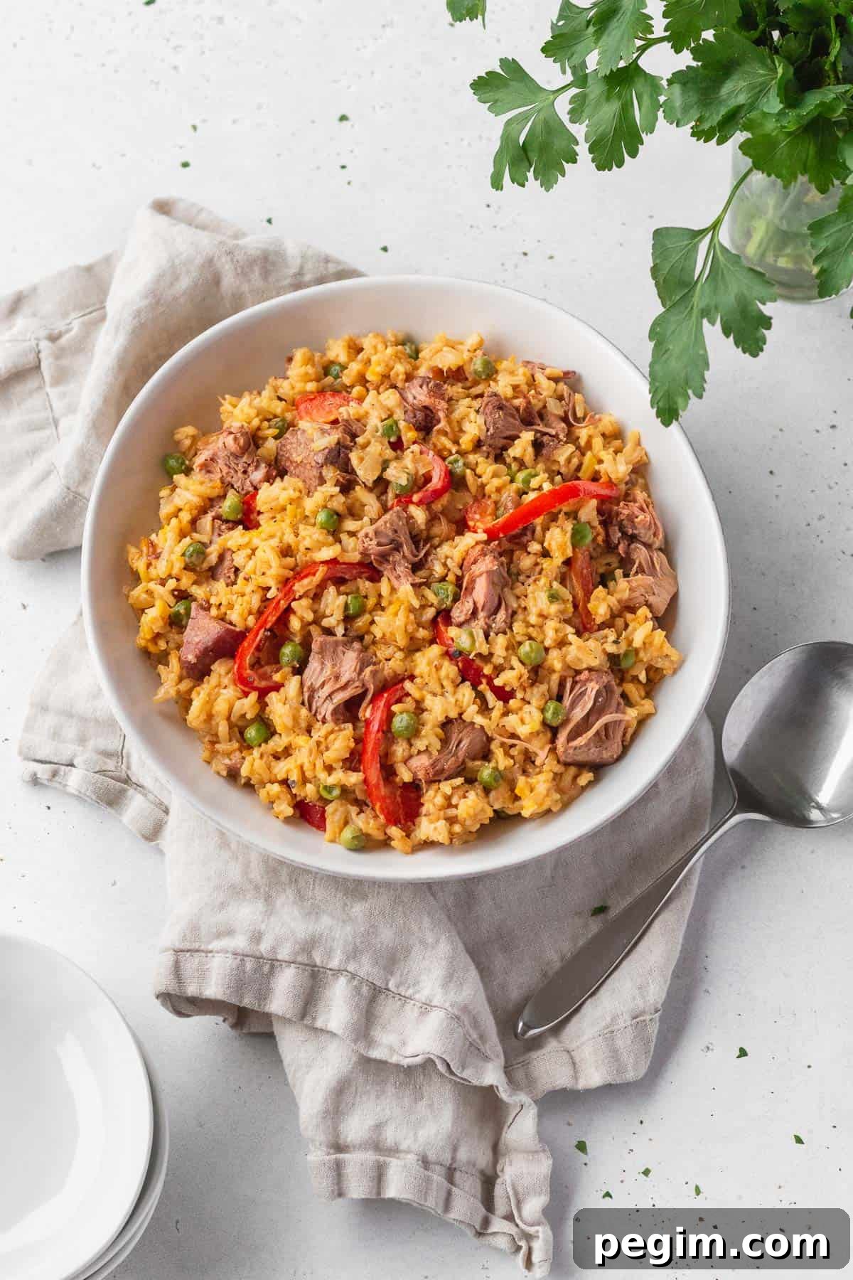 Vegan Arroz a la Valenciana: Spanish-Style Rice with Vegetables 2 Overhead shot of vegan Arroz Valenciana in a white bowl with a spoon and natural linen.