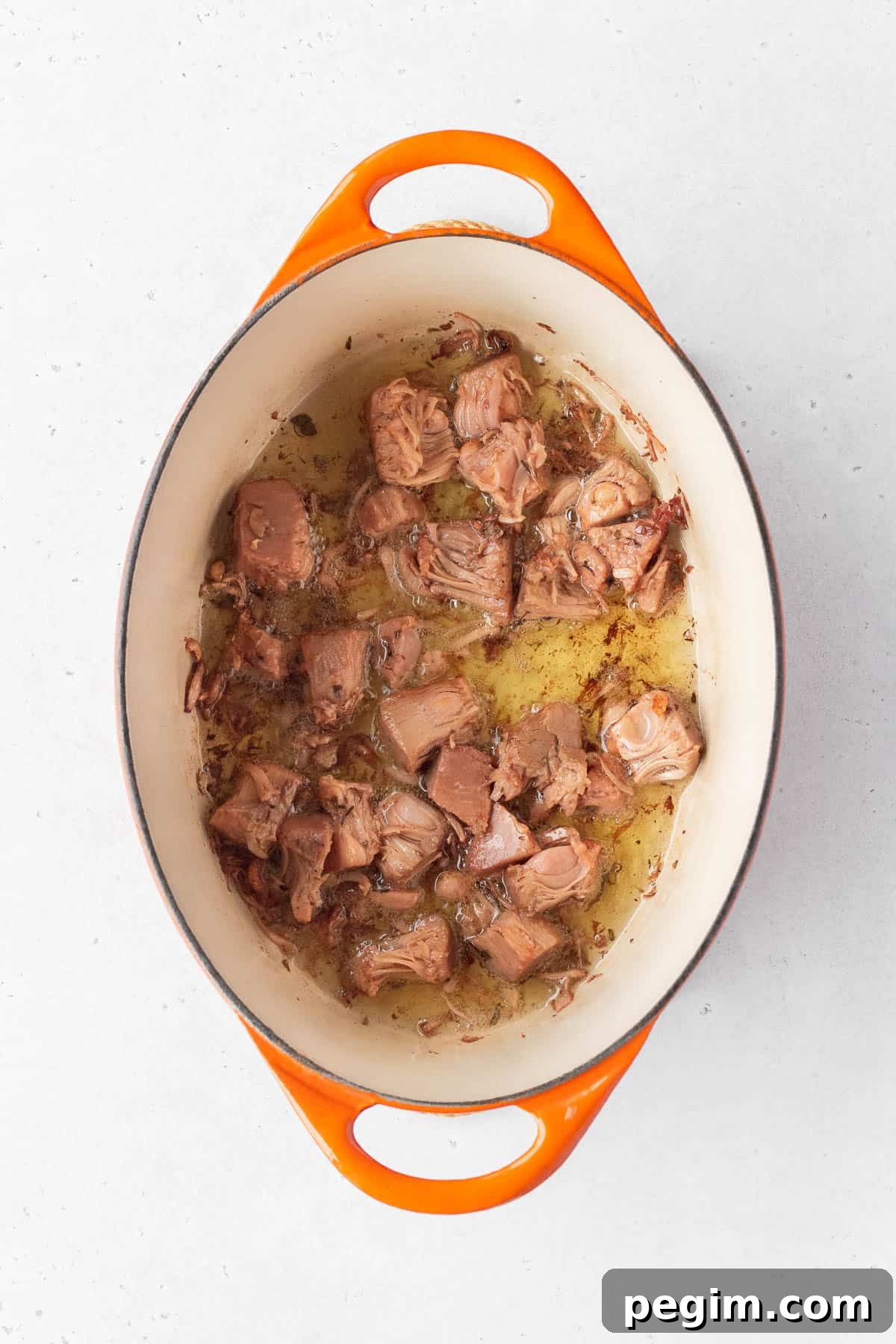 Vegan Arroz a la Valenciana: Spanish-Style Rice with Vegetables 5 Young green jackfruit confit being cooked in oil in a pot.