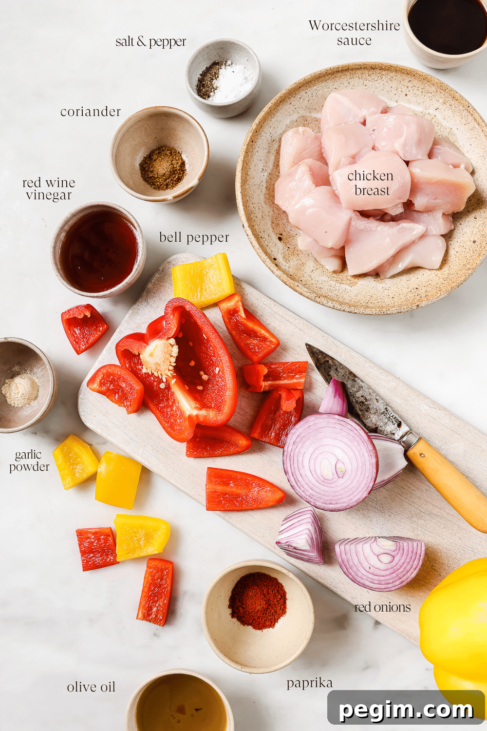Prepped ingredients for chicken kabobs on a white countertop.