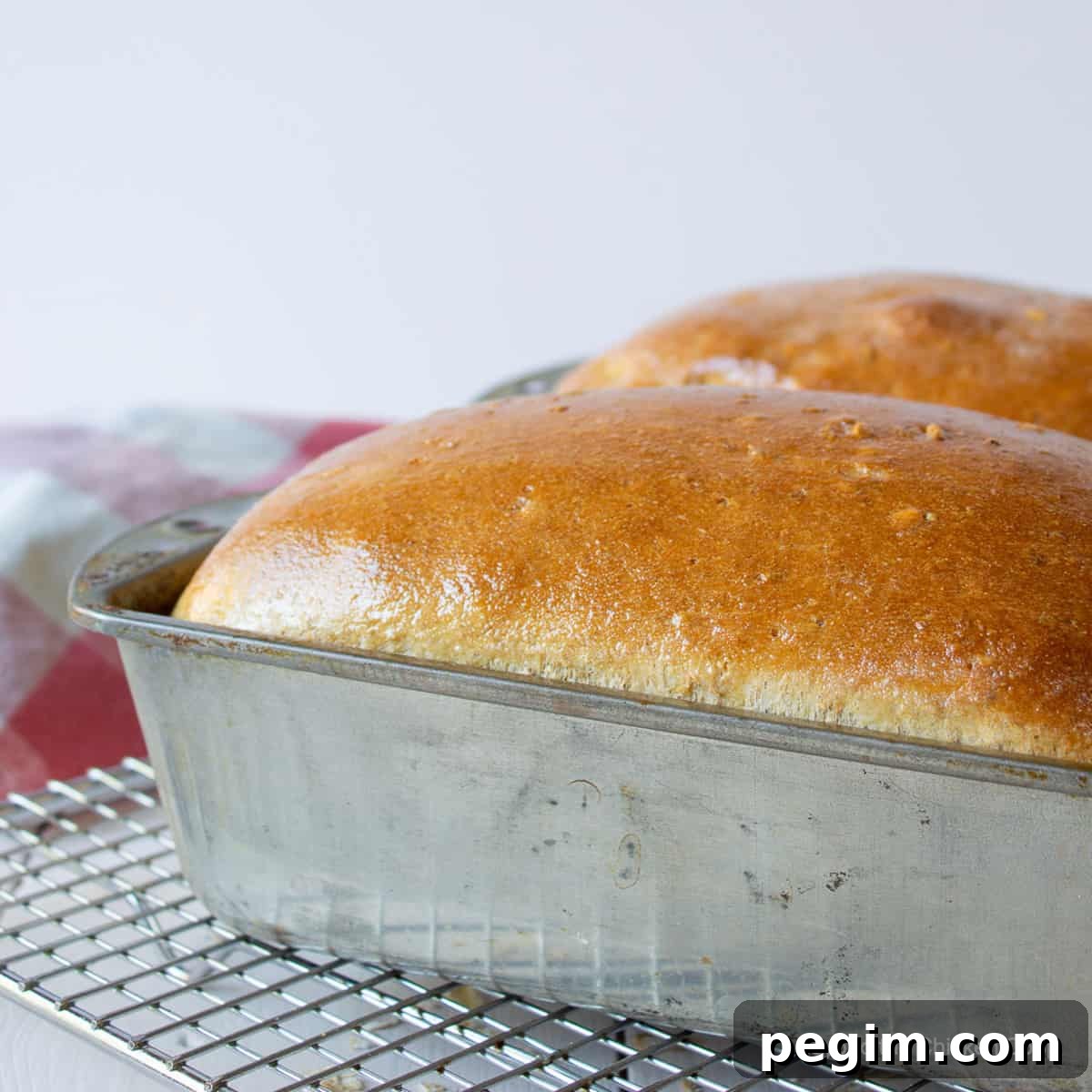Soft Homemade White Wheat Bread Recipe 6 Two loaves of cooked bread in a metal bread pan.