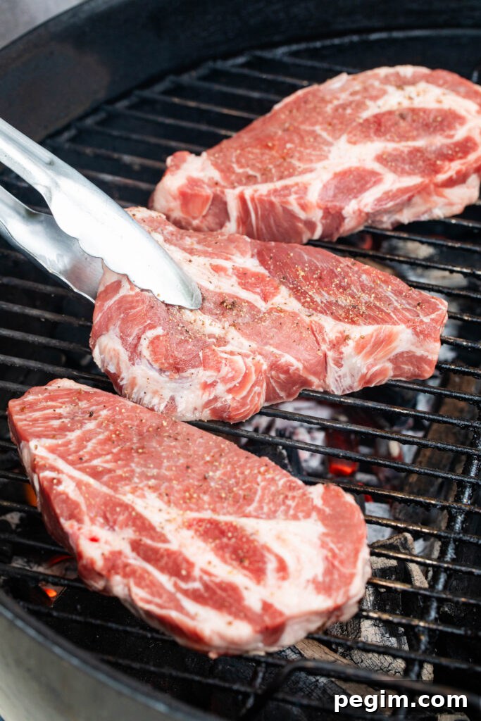 placing three pork coppa steaks on the grill over lit coals